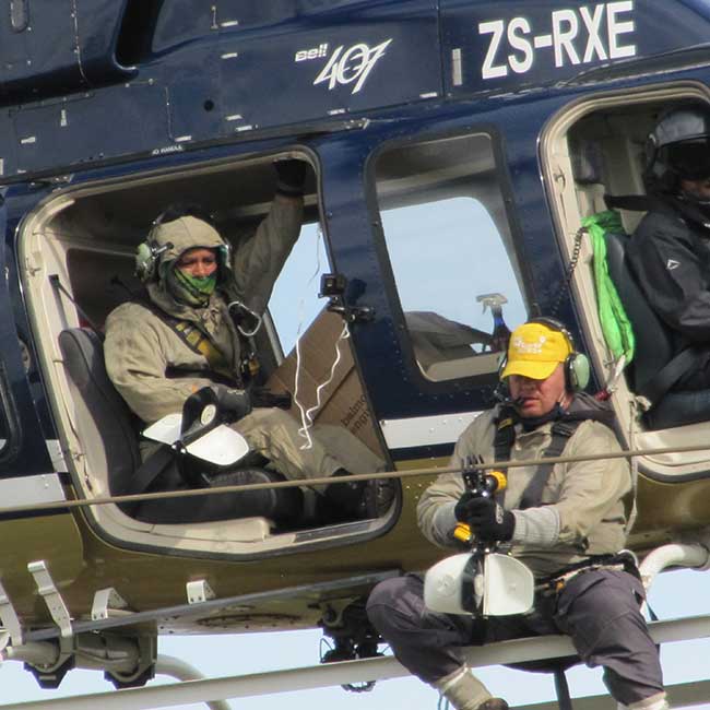 men hanging from helicopter to mark power line